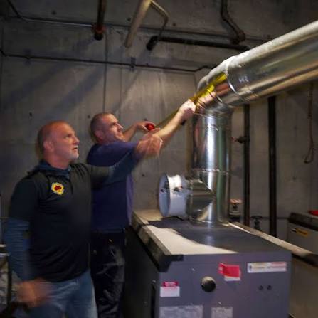Two experienced technicians working together on an appliance vent