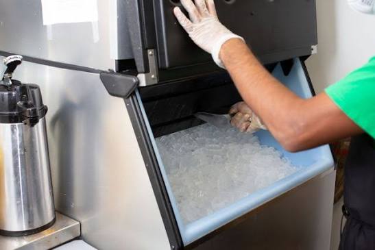Commercial ice machine being serviced in a restaurant kitchen