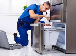 Technician repairing a stainless steel refrigerator with a laptop